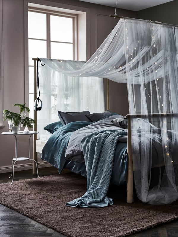 Sheer curtains around a bed on high legs