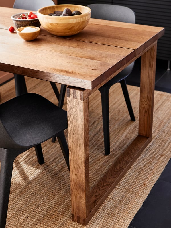 A brown stained oak veneer MÖRBYLÅNGA table and some anthracite ODGER chairs stand in a dining room.
