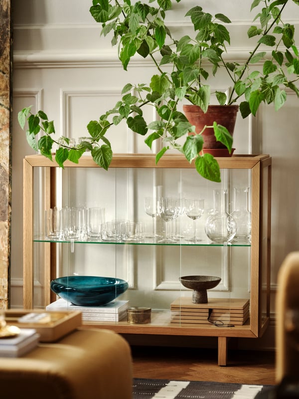 An oak veneer STOCKHOLM 2025 glass-door cabinet in the living room