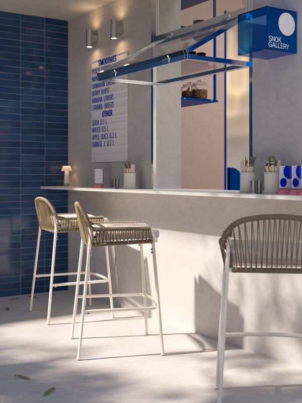 An outdoor café bar with an open window, cozy lighting, a menu on the wall and three white/beige SEGERÖN outdoor bar stools.