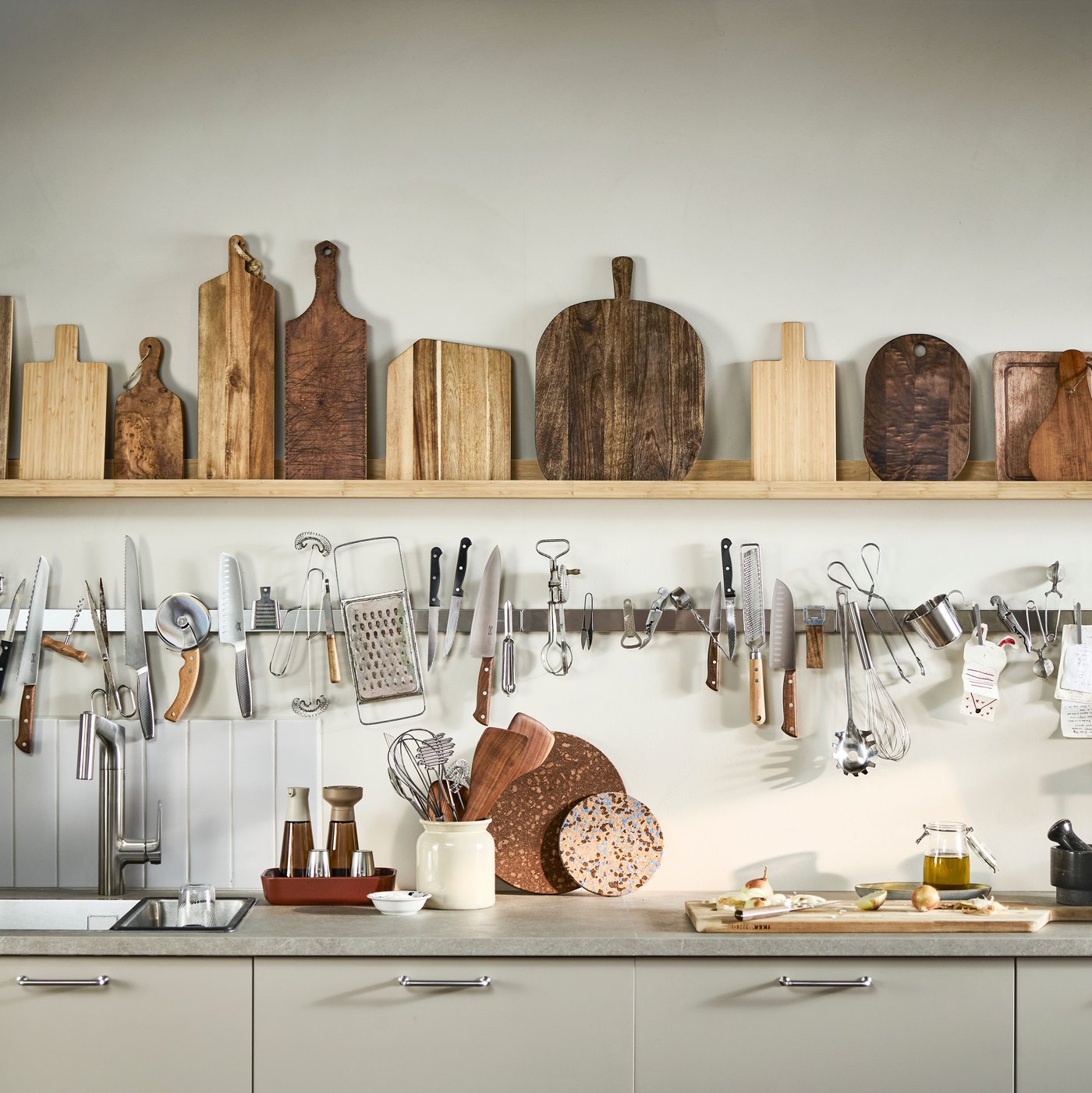 A light-coloured kitchen with narrow shelves holding wooden cutting boards and KUNGSFORS magnetic knife racks.