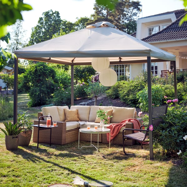 Outdoor Möbel stehen unter einem Sonnenschirm in einem Garten.