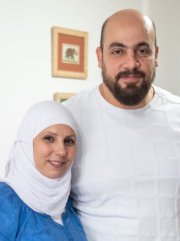 Potrait of a women and a man standing in a room inside smiling towards the camera. 