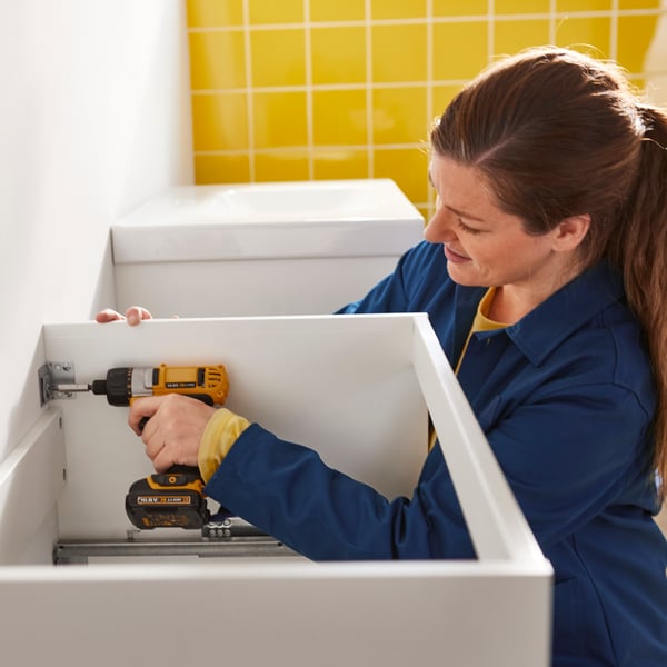 Woman installing bathroom cabinet