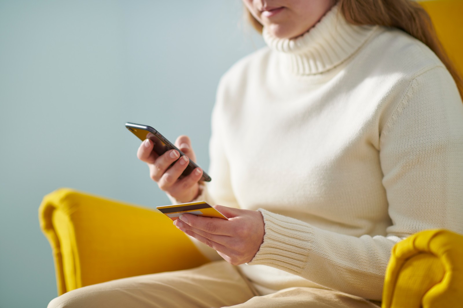 Žena drži platnu karticu i telefon u ruci.