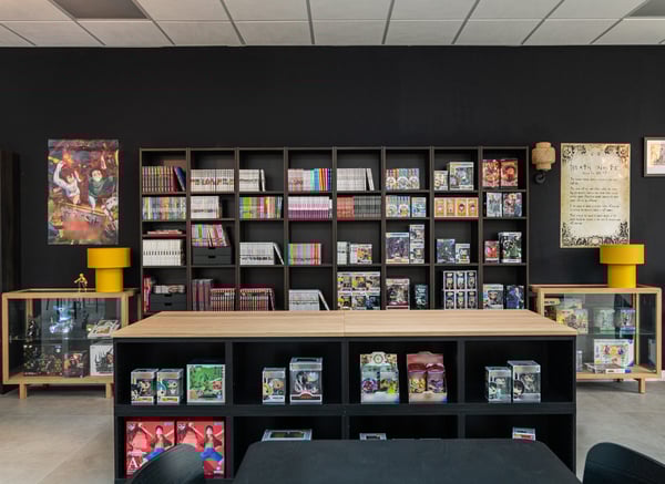 Un bancone a centro stanza della serie BESTÅ con alle spalle una libreria BILLY nera e ai lati due vetrine STOCKHOLM 2025.