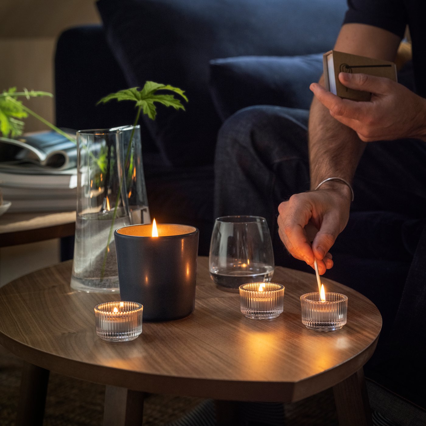 Someone is lighting candles and scented candles on a coffee table using a match.
