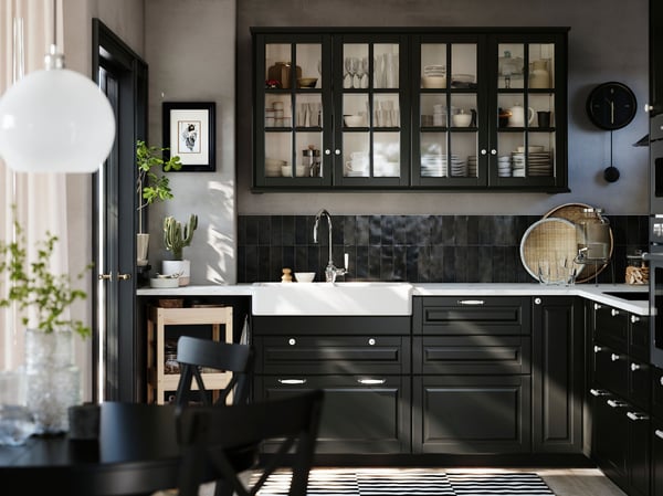 A kitchen has black BODBYN fronts with bevelled edges on the base cabinets and black BODBYN glass doors on the wall cabinets.