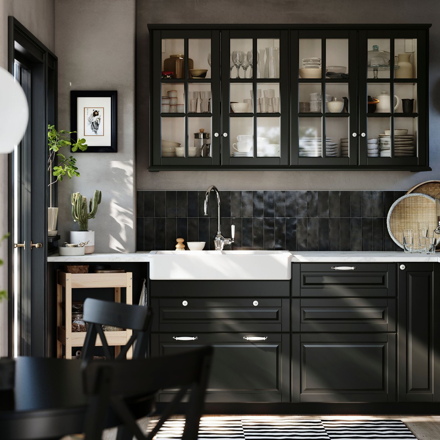 A kitchen has black BODBYN fronts with bevelled edges on the base cabinets and black BODBYN glass doors on the wall cabinets.