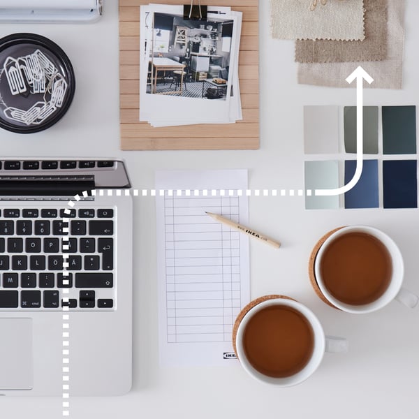 ノートPCとメモ、インテリア写真、色見本と布サンプル、コーヒーが並ぶワークスペースでインテリアプランニング