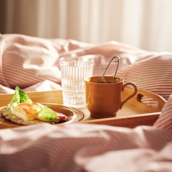 Tasse de thé jaune sur un plateau, dans un lit