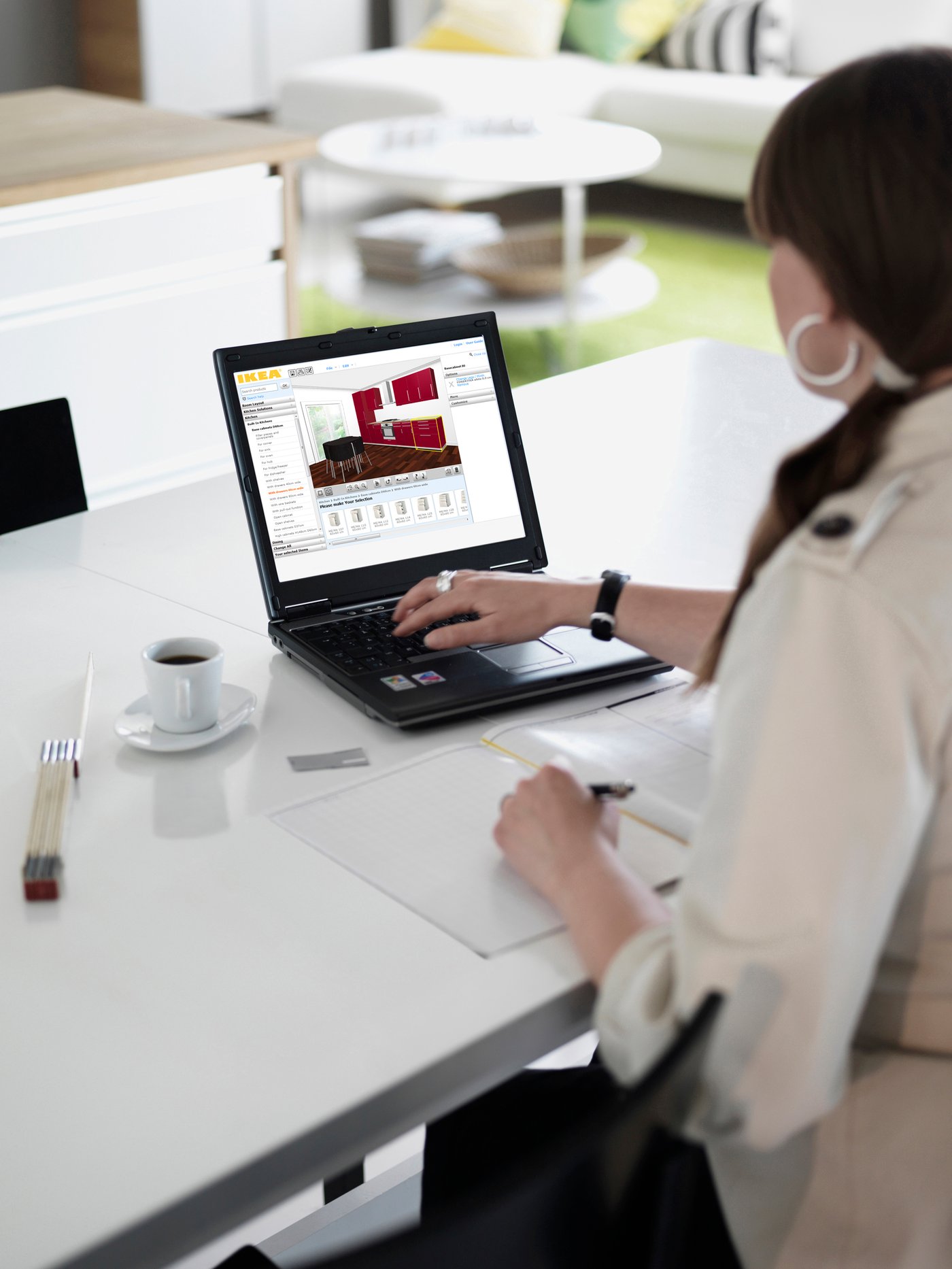 Man sieht eine Frau die eine Hand auf ihrem Laptop hat und eine Küche im IKEA Küchenplaner plant.