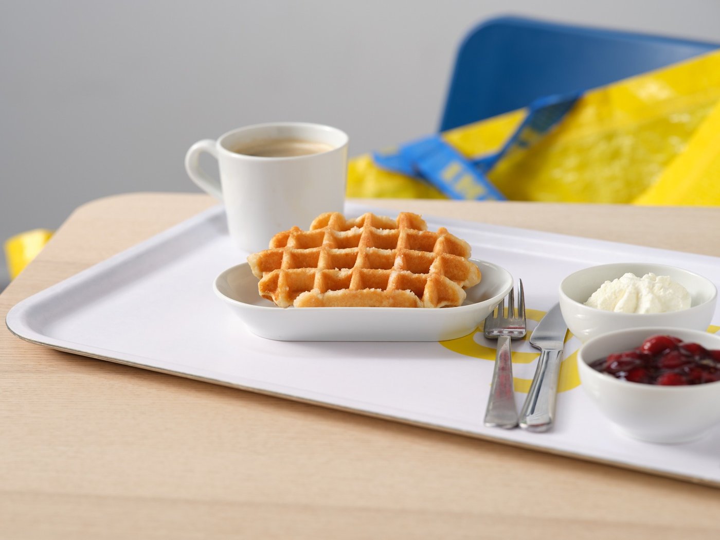 Een IKEA dienblad met een wafel, kersencompote en slagroom en een mok met koffie in het Zweeds restaurant.