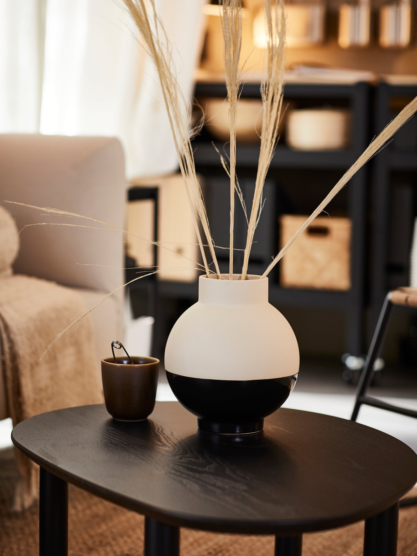 A black and white vase on a black table.
