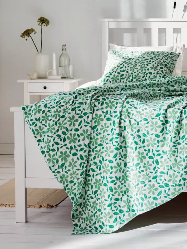 Hvidt gardin med et grønt mønster af figengrene vist ved siden en loftlampe af naturlige bananfibre.