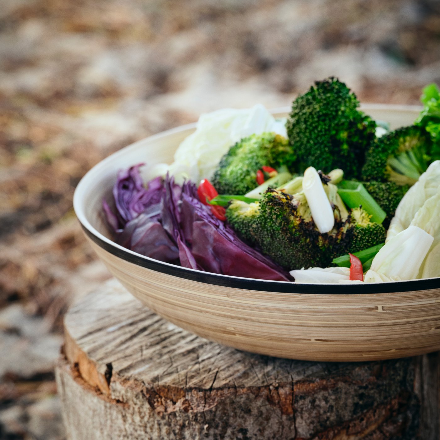 En SOLUPPGÅNG serveringsskål fremstillet af bambus er fyldt med friske og farverige grøntsager.