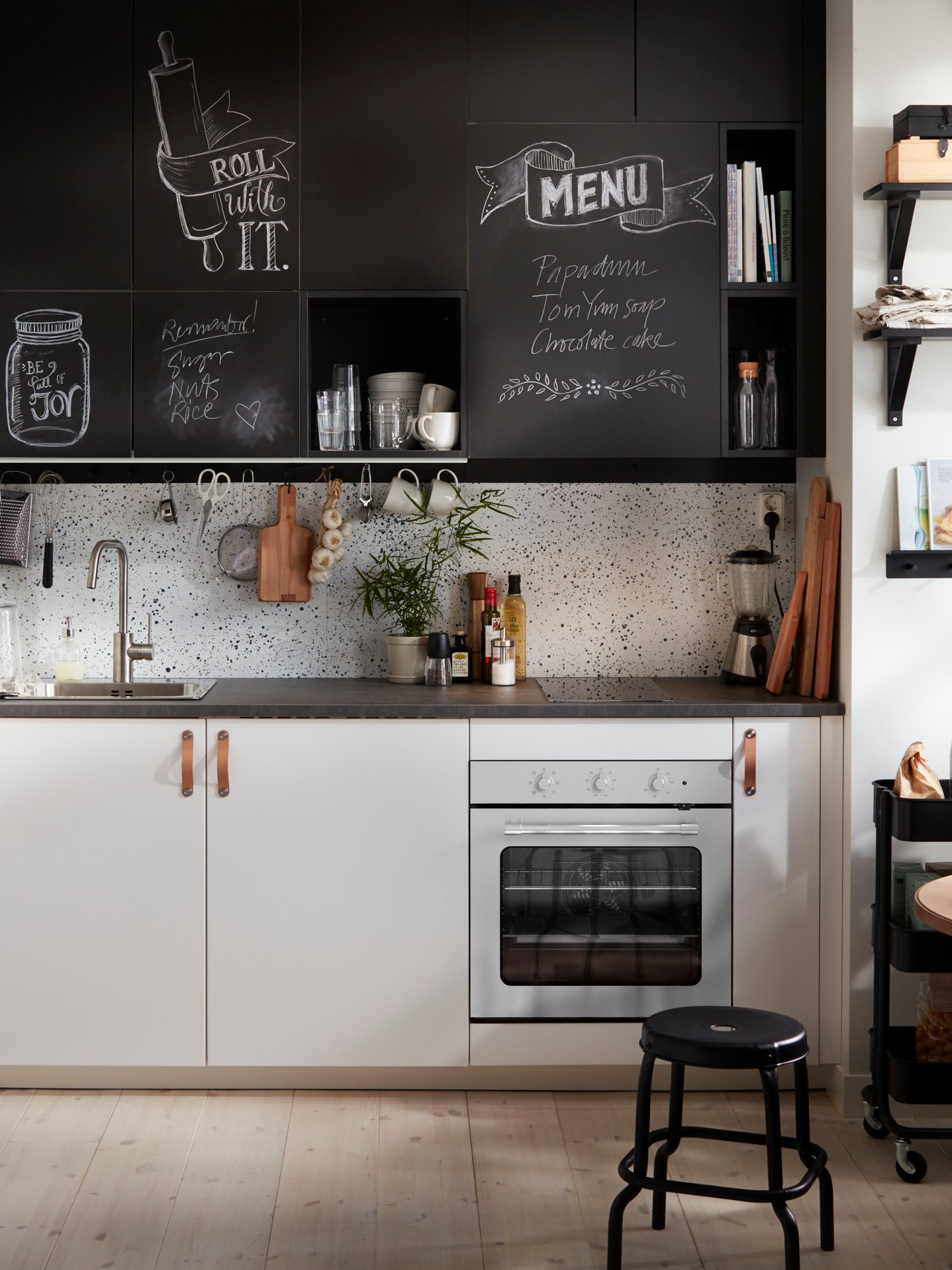 Cocina con puertas integradas en un armario bajo, un horno de aire, una puerta con superficie de pizarra, un taburete y un armario de pared.