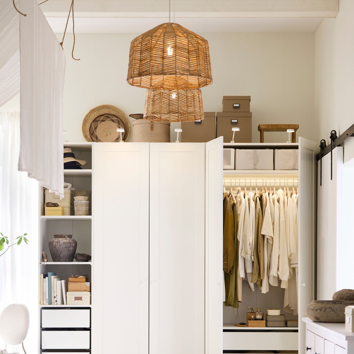 Dos pantallas de lámpara colgante KAPPELAND de ratán colgadas cerca de una combinación de armario PAX/GULLABERG blanca con iluminación para armarios YTBERG.