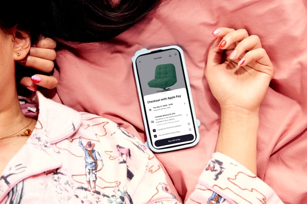 Eine Frau, die im Bett liegt und nebenei ihr Handy mit der offenen IKEA App liegen hat.