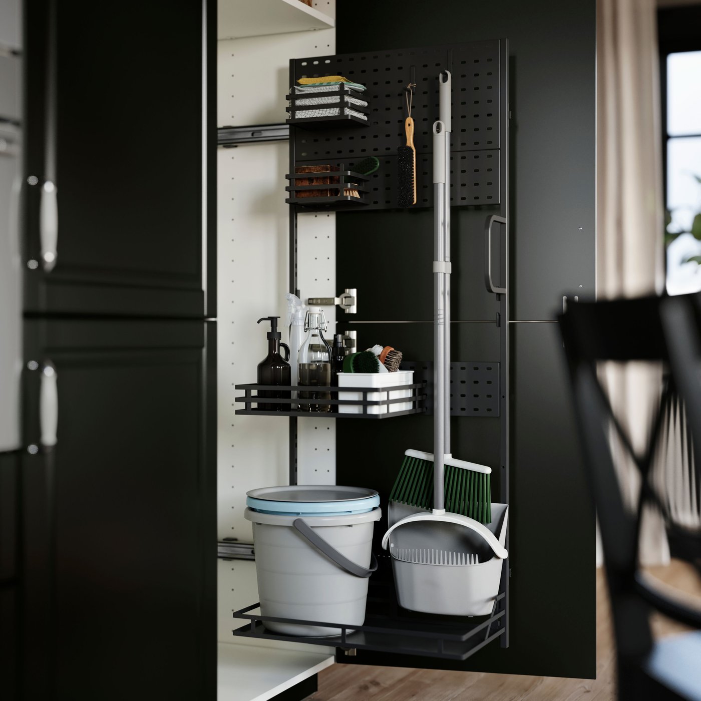 Un mobile per la cucina con un'anta aperta che mostra un accessorio interno per i prodotti per le pulizie UTRUSTA con ripiani in filo di metallo regolabili su cui sono organizzati detergenti e accessori per le pulizie.