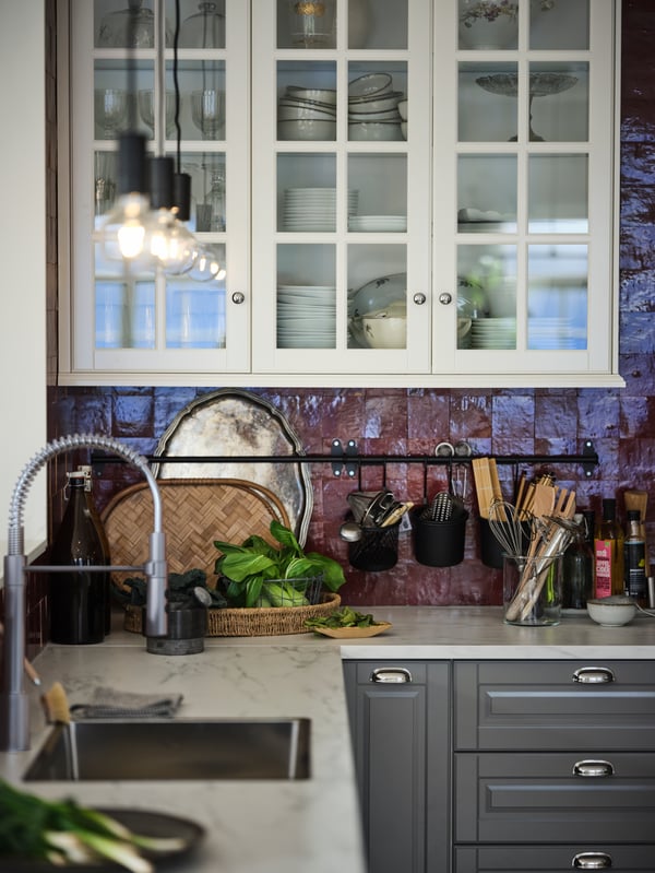 An EKBACKEN white-marble-effect worktop with grey METOD cabinets with MAXIMERA interiors in a red-tiled kitchen.