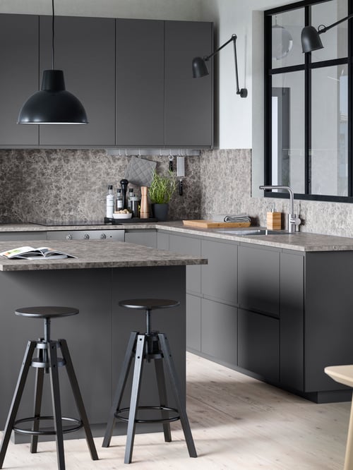 Kitchen with wall lamps surrounding a window, wall cabinets, a base cabinet with fronts and drawers, and a bar stool.