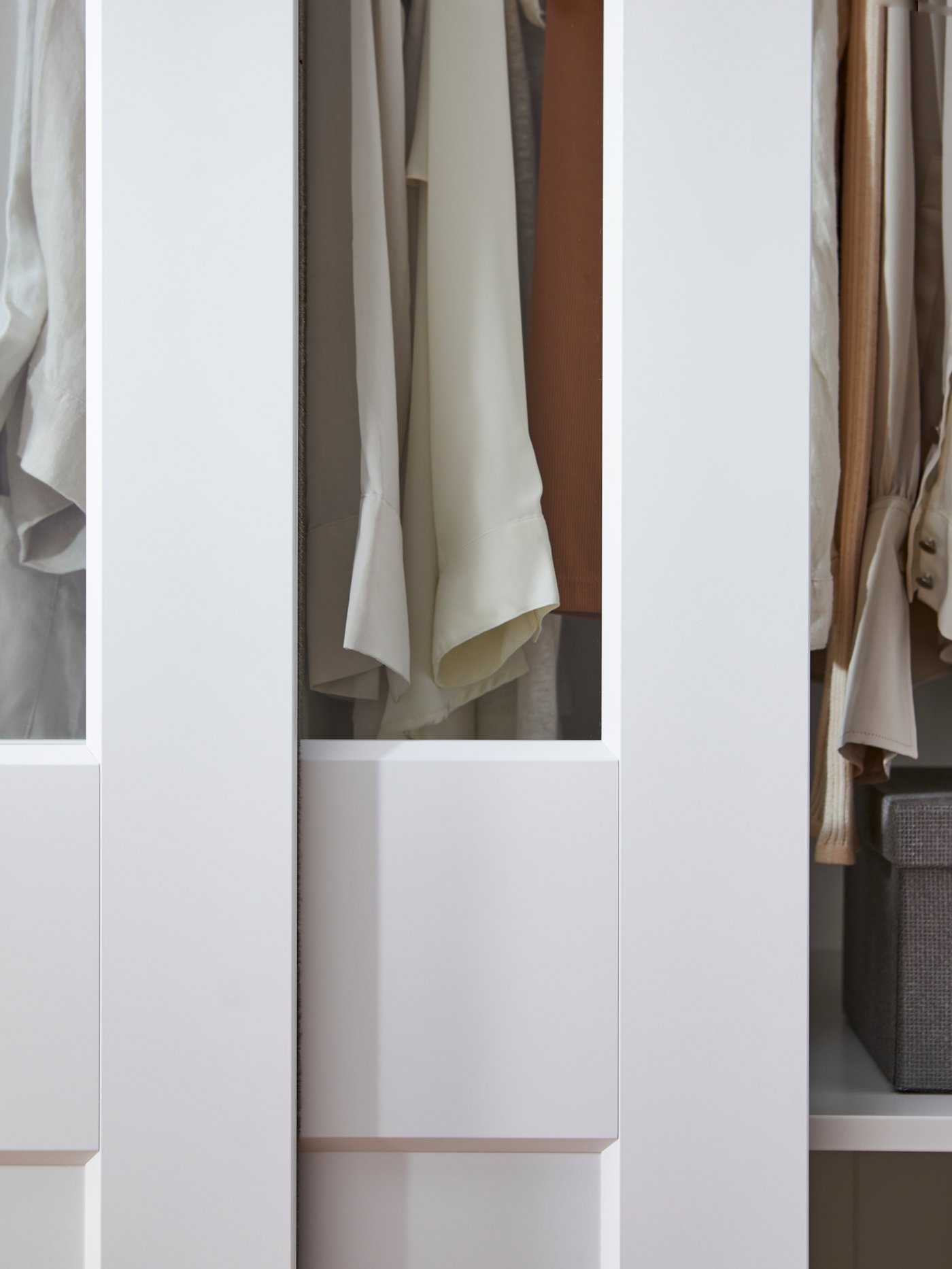 En vit PAX garderob med skjutdörrar i vitt och klart spegelglas.
