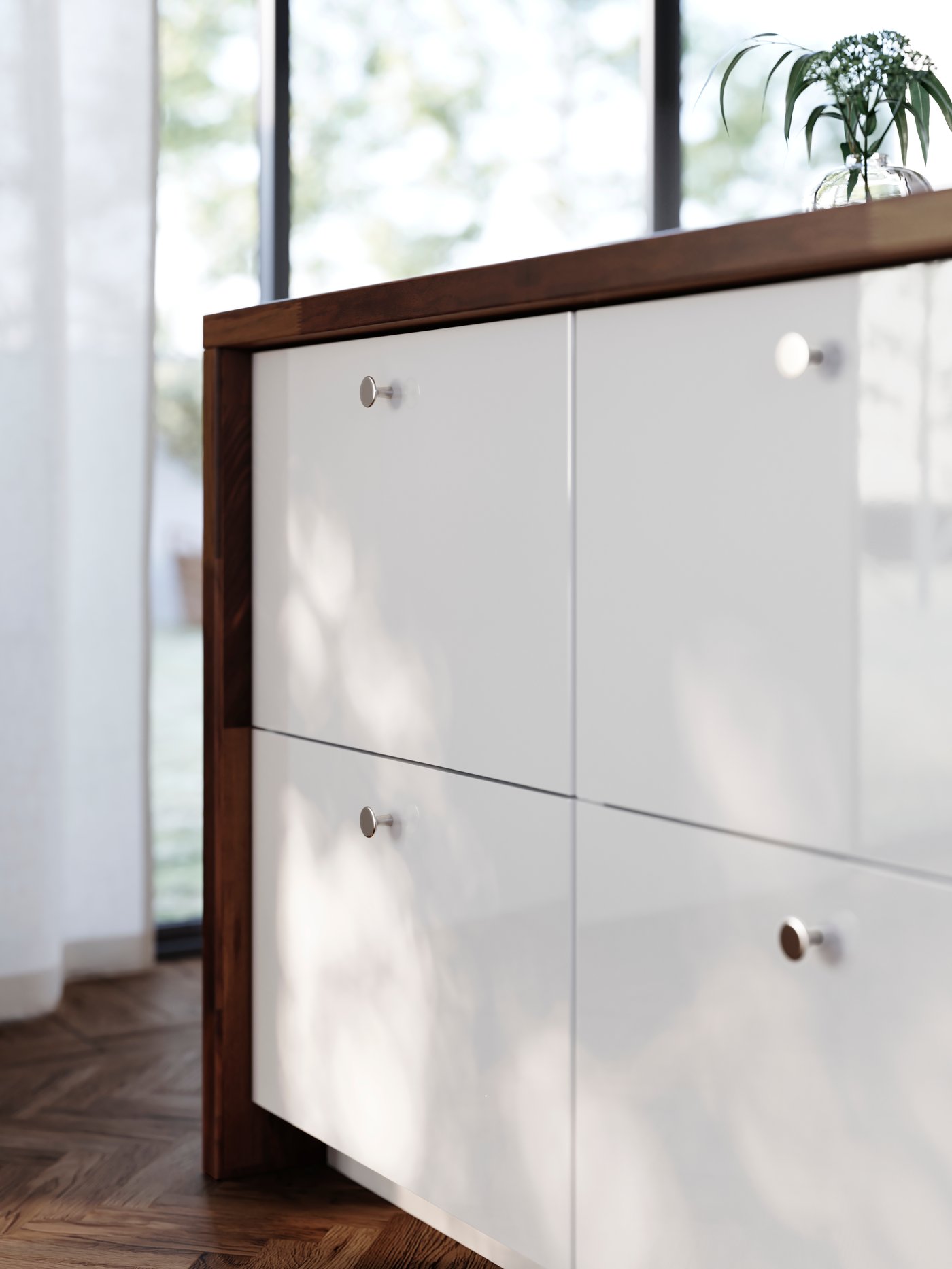 A large kitchen island has four drawers with high-gloss white RINGHULT fronts and KALERUM knobs in a stainless steel colour.