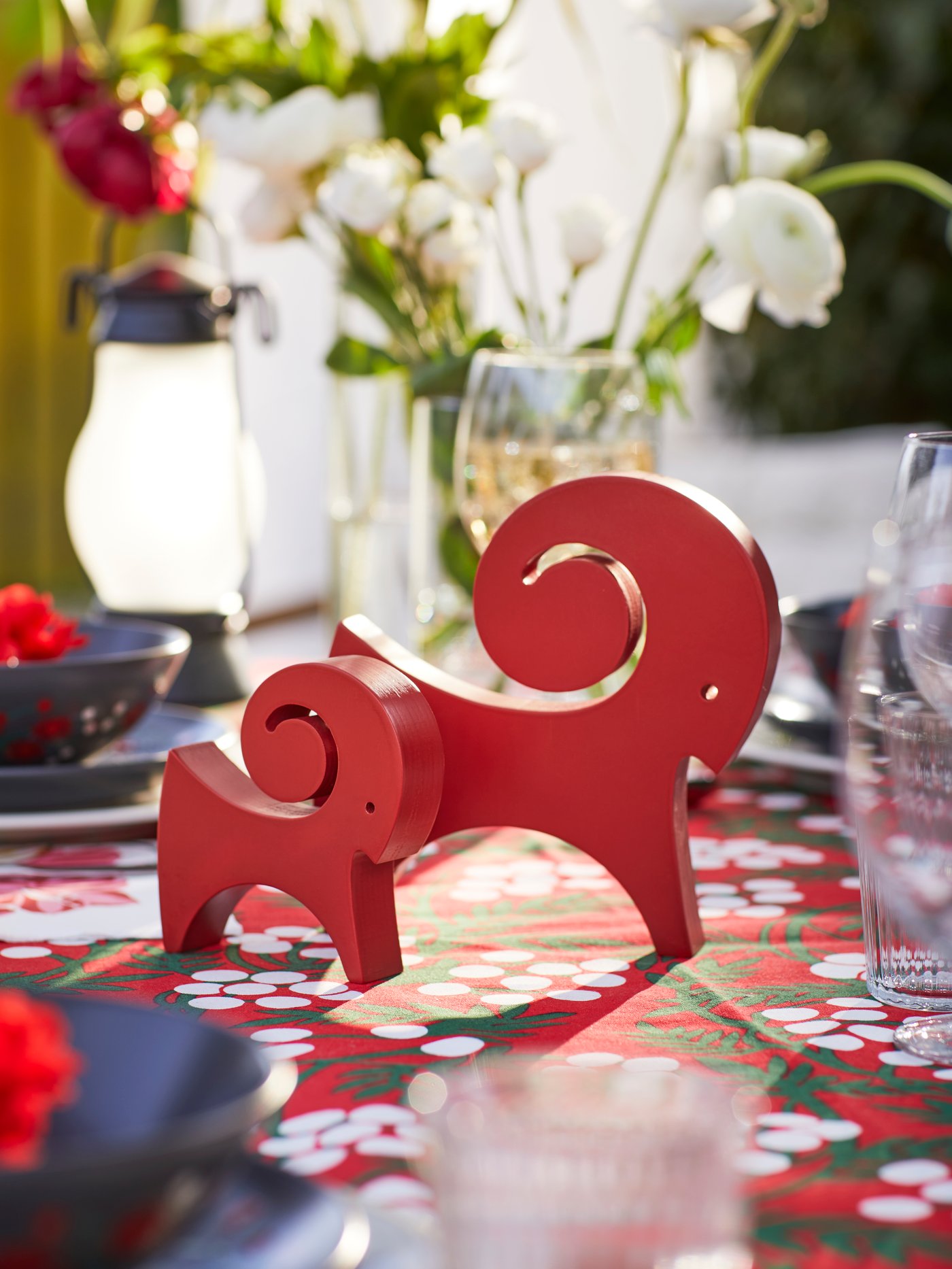 Dos adornos de cabras rojas de la colección VINTERFINT sobre una mesa navideña.