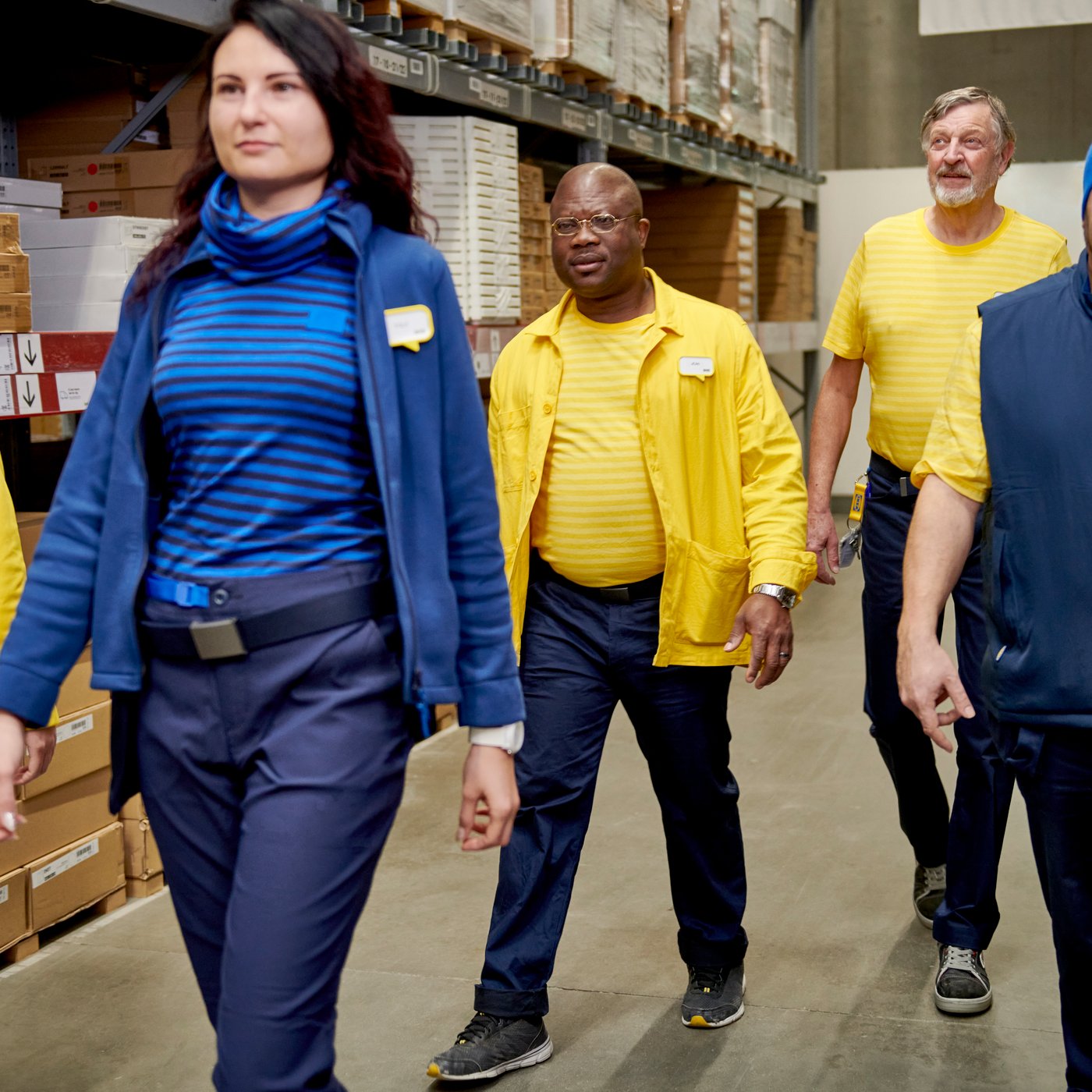 A group of IKEA employees are walking between the shelves.