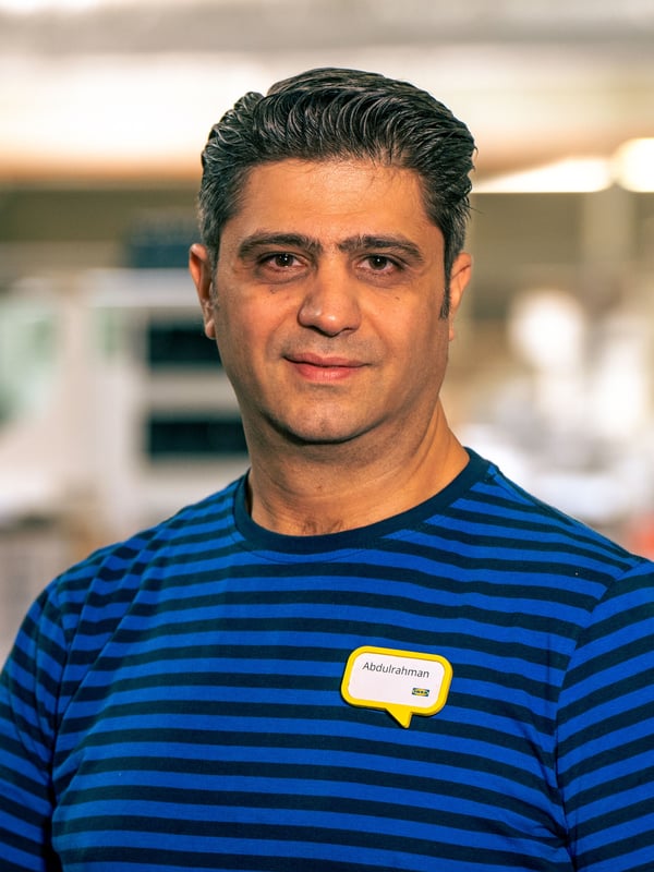 Abdul standing in the IKEA store wearing his blue work uniform.