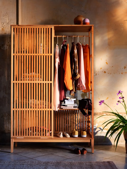 Schlafzimmer mit offenem Kleiderschrank mit Schiebetür, Kleiderbügel, Bücher und Schuhe in Regalen, runde Vasen, Übertöpfe.