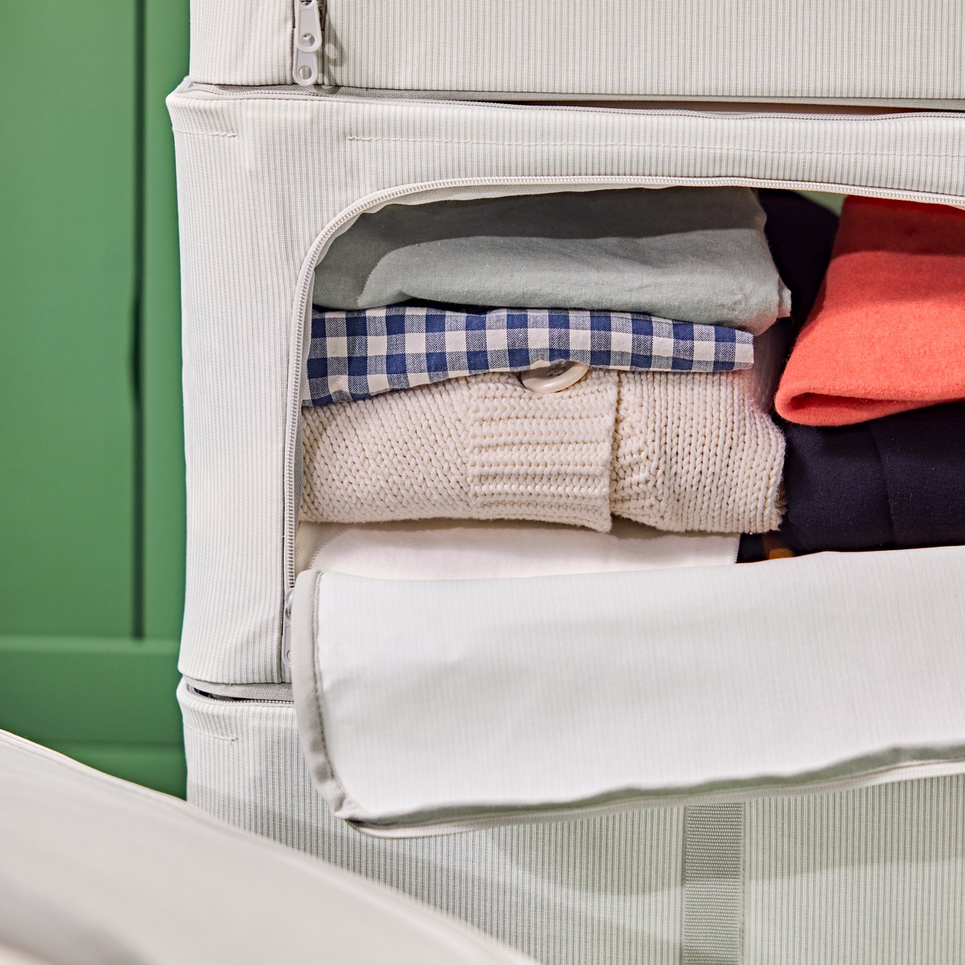 Detail of three stacked HEMMAFIXARE storage bags. One of them is partially open and has clothes inside.