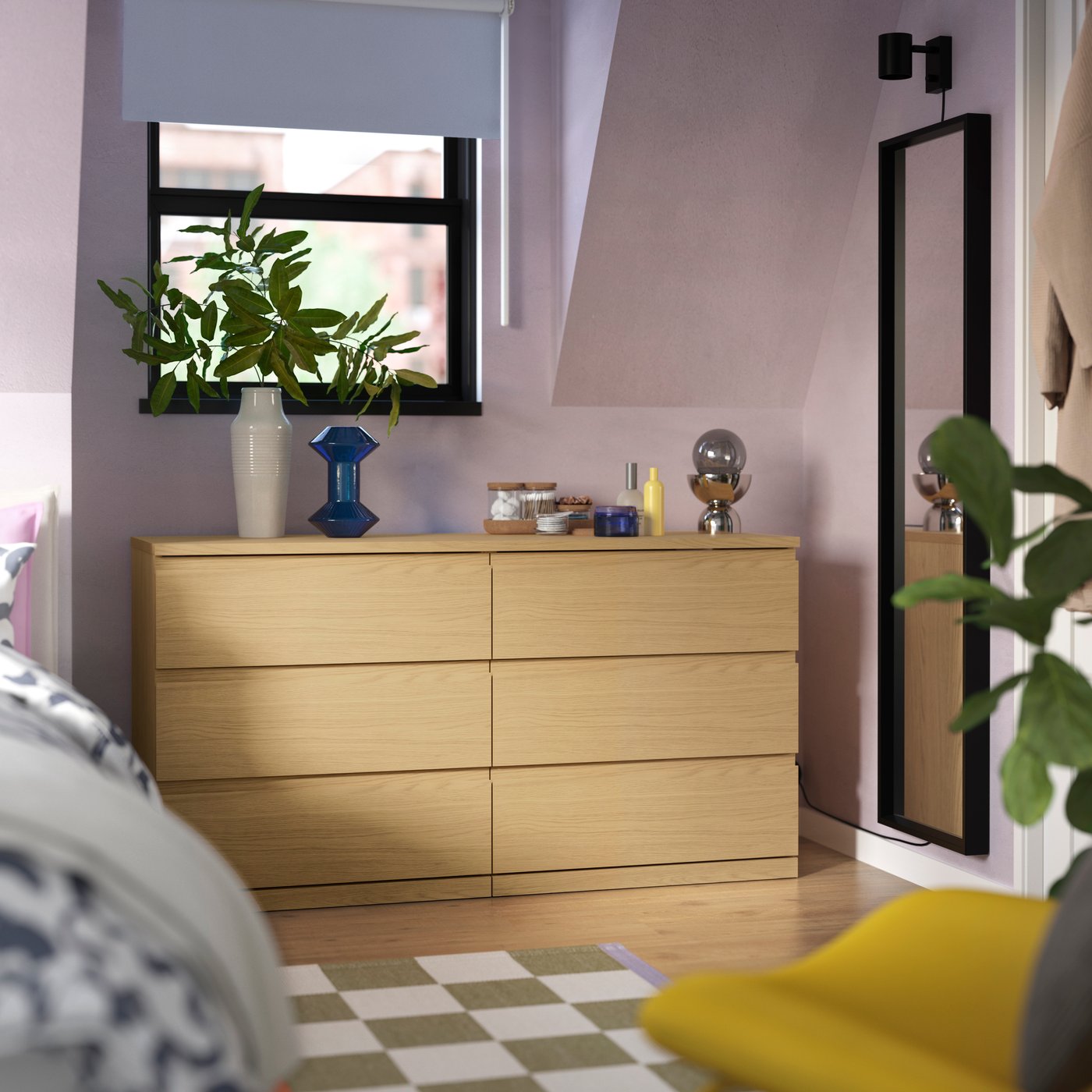 STORKLINTA wood dresser in a colorful bedroom, topped with plants and decor near a tall mirror.