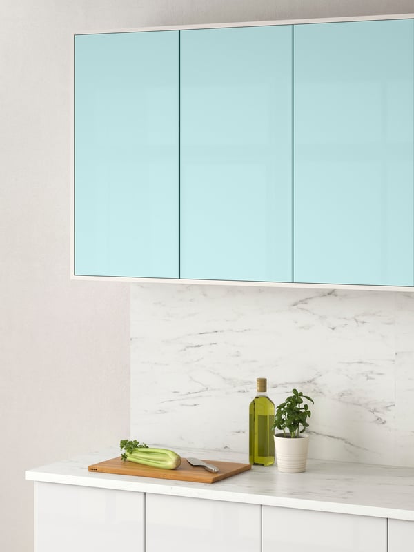 A kitchen, wall cabinets with JÄRSTA kitchen fronts in light turquoise above an EKBACKEN marble effect laminate worktop.