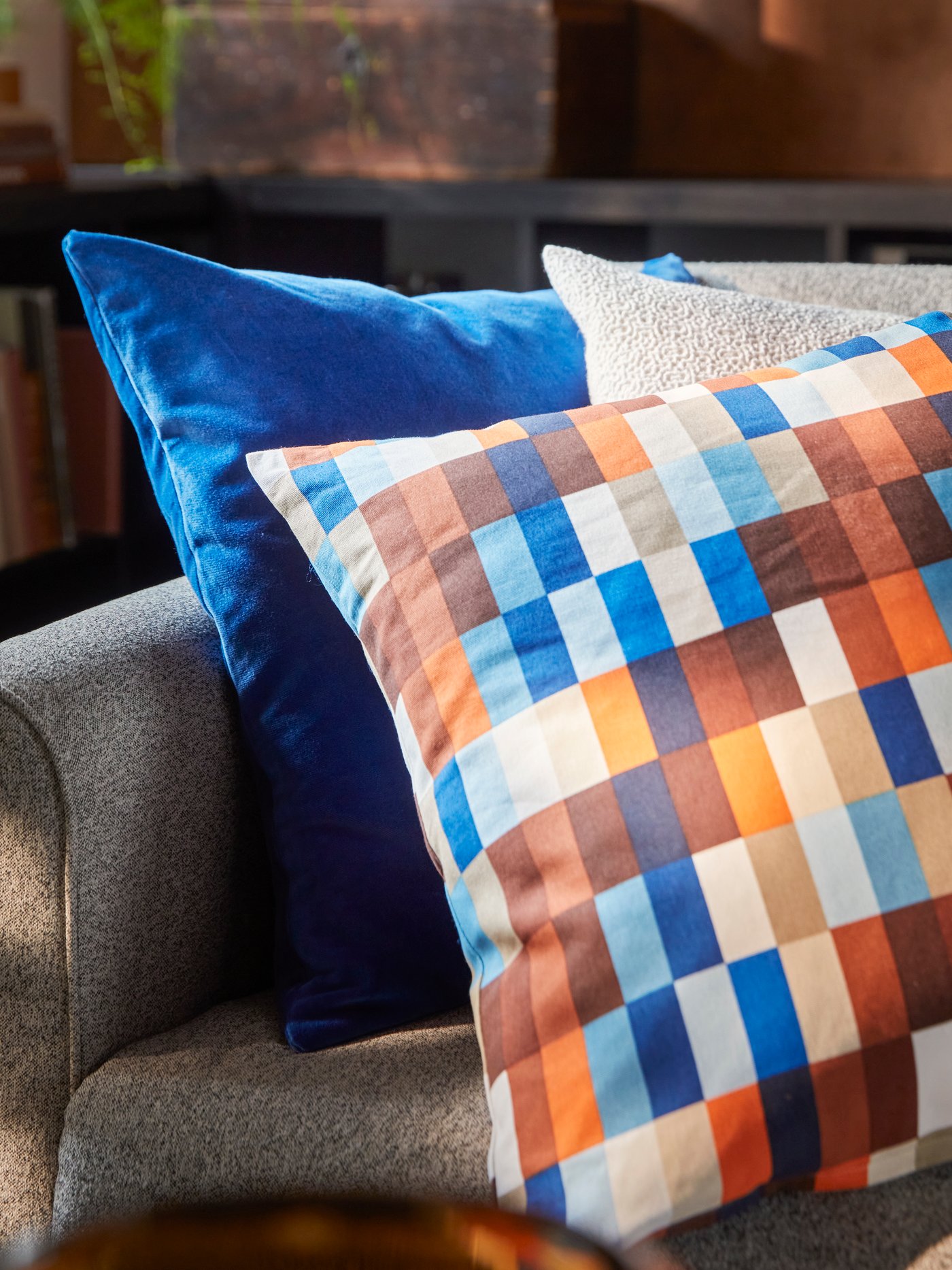 En soffa med färgstarka rutiga prydnadskuddar i blått, orange och vitt.