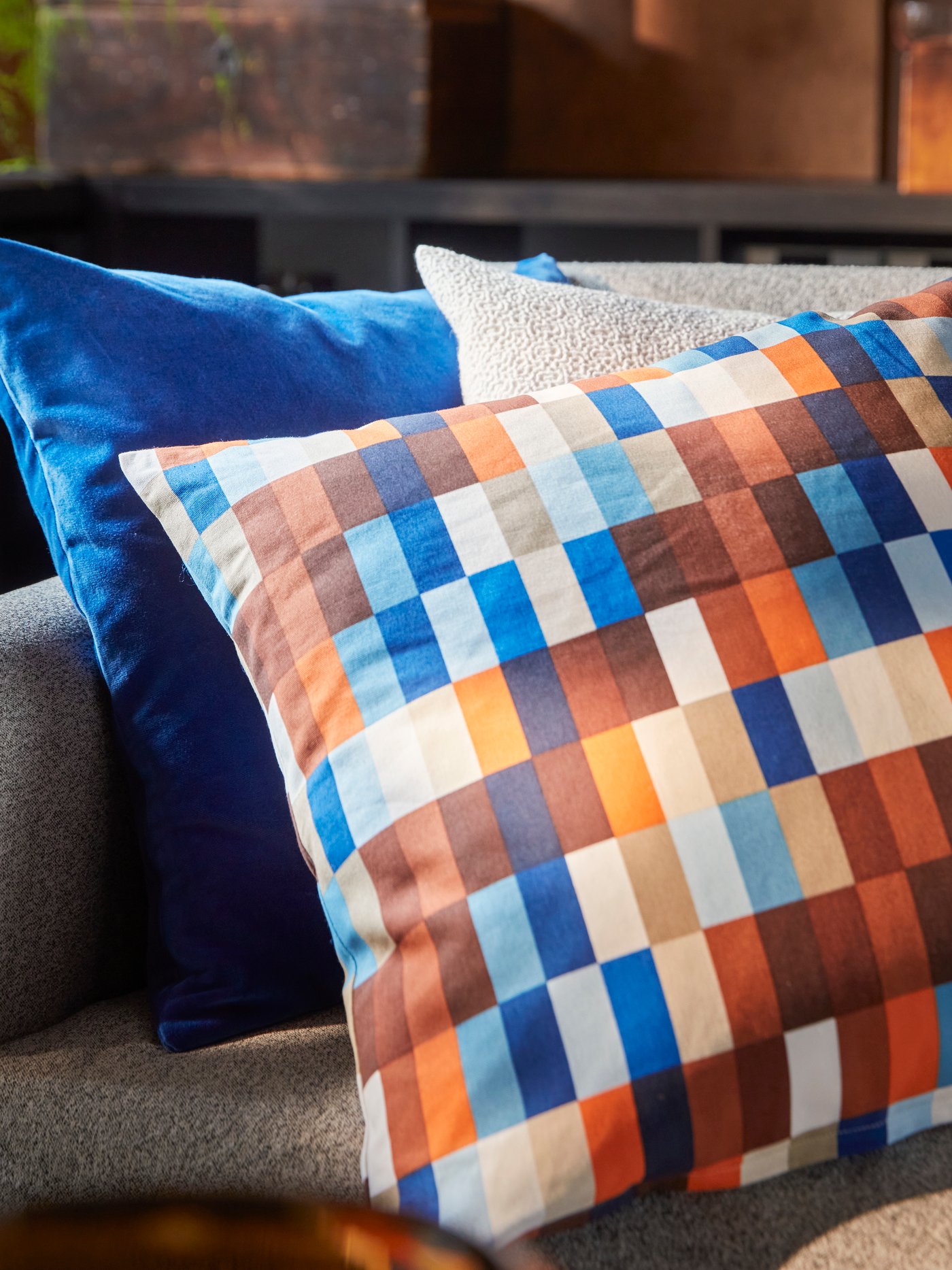 A close-up of a SALTMYRAN 3-seat sofa with a brown/blue LÖVNATURSKOG cushion cover and two other cushions.