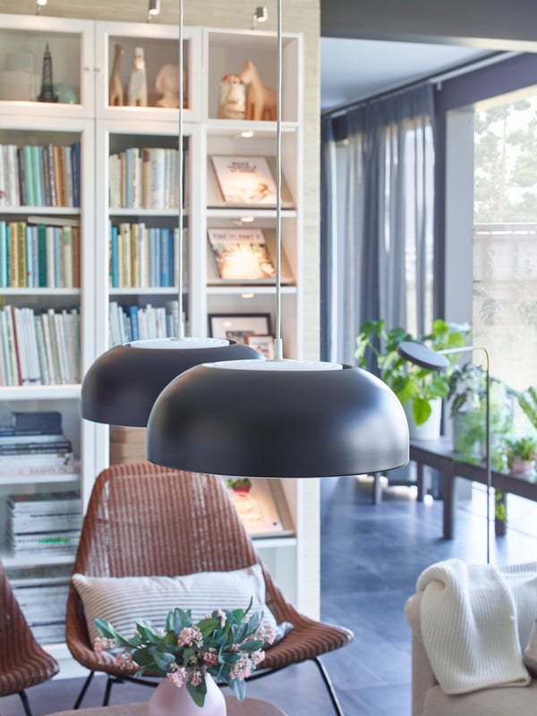 IKEA NYMÅNE black anthracite pendant lamps hanging over a coffee table in a living room.