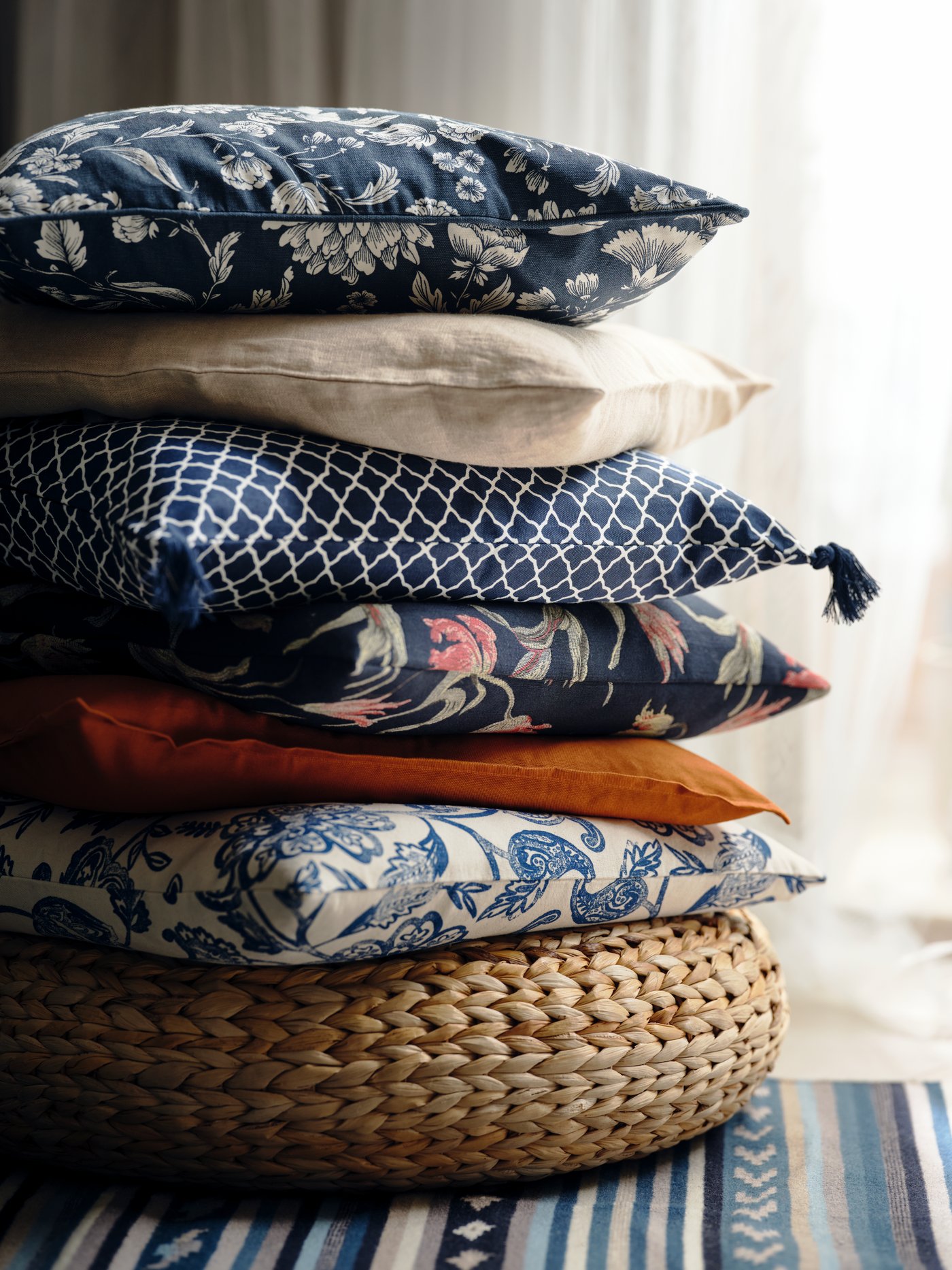 A blue/white/floral patterned IDALINNEA cushion cover in the living room