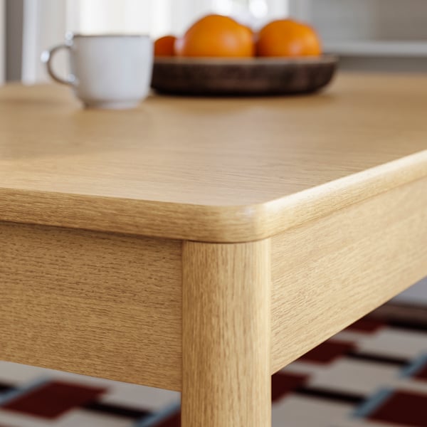 A corner shot of an oak veneer TONSTAD extendable table