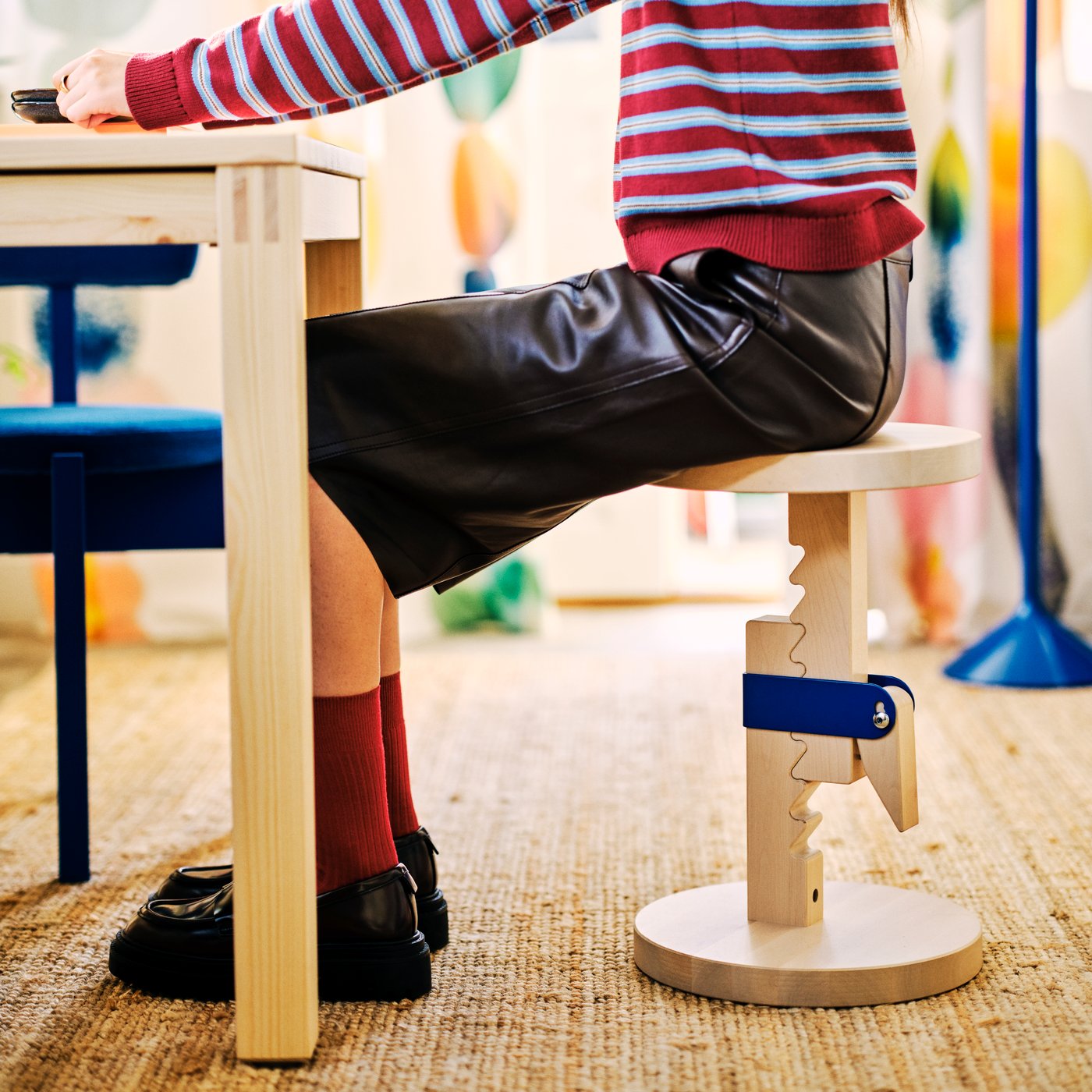 A person sits on an IKEA PS 2026 stool that’s height adjustable.