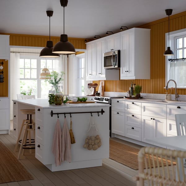 A kitchen featuring white cabinets, a central island with stools, and warm wooden walls, creating a bright, welcoming space.
