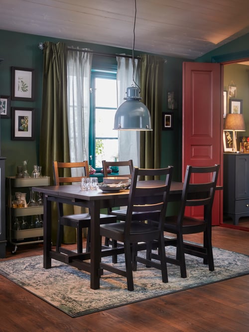 Dining room with a set of rectangular dark brown wooden table and 4 chairs on top of a rug low pile, and a pendant lamp.