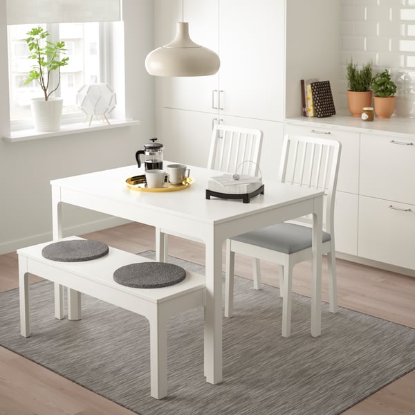 EKEDALEN extendable dining table in white with 2 chairs and a bench in a diing room area with a ceiling pendant lamp hanging above it. 