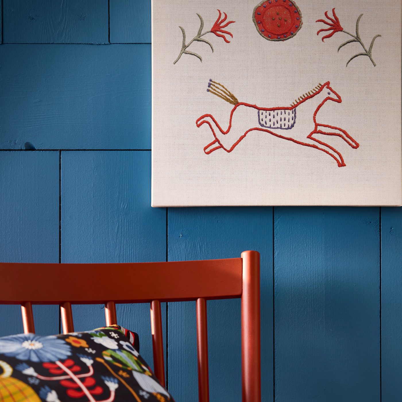 A PJÄTTERYD picture featuring a red horse running and decorative motifs is displayed against a blue wall.