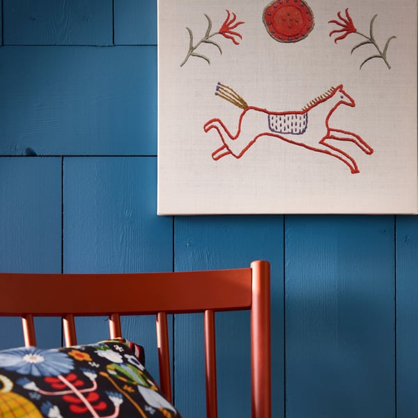 A PJÄTTERYD picture featuring a red horse running and decorative motifs is displayed against a blue wall.