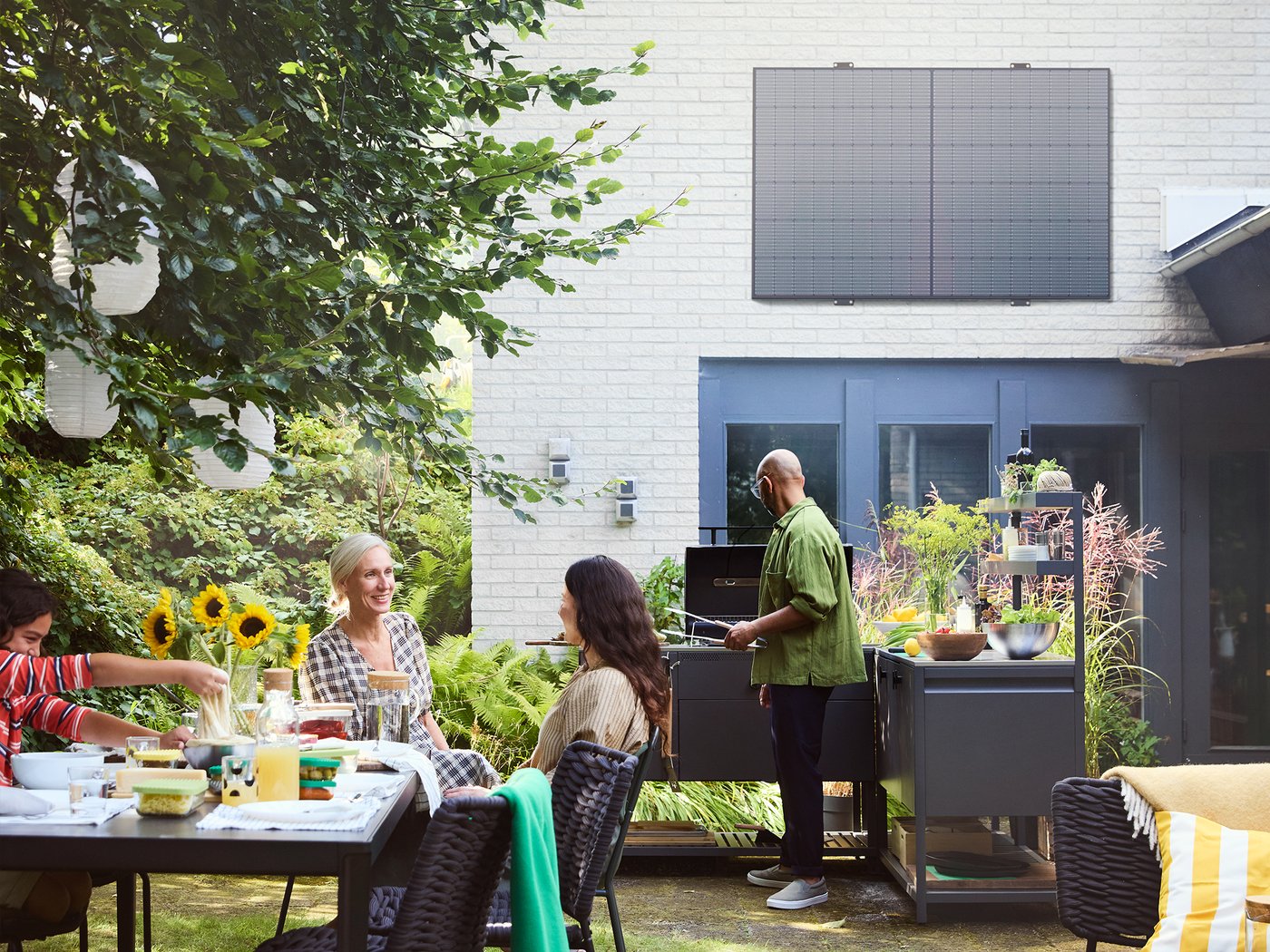 Ein Garten mit Tischen und Stühlen, indem Personen stehen und sitzen.