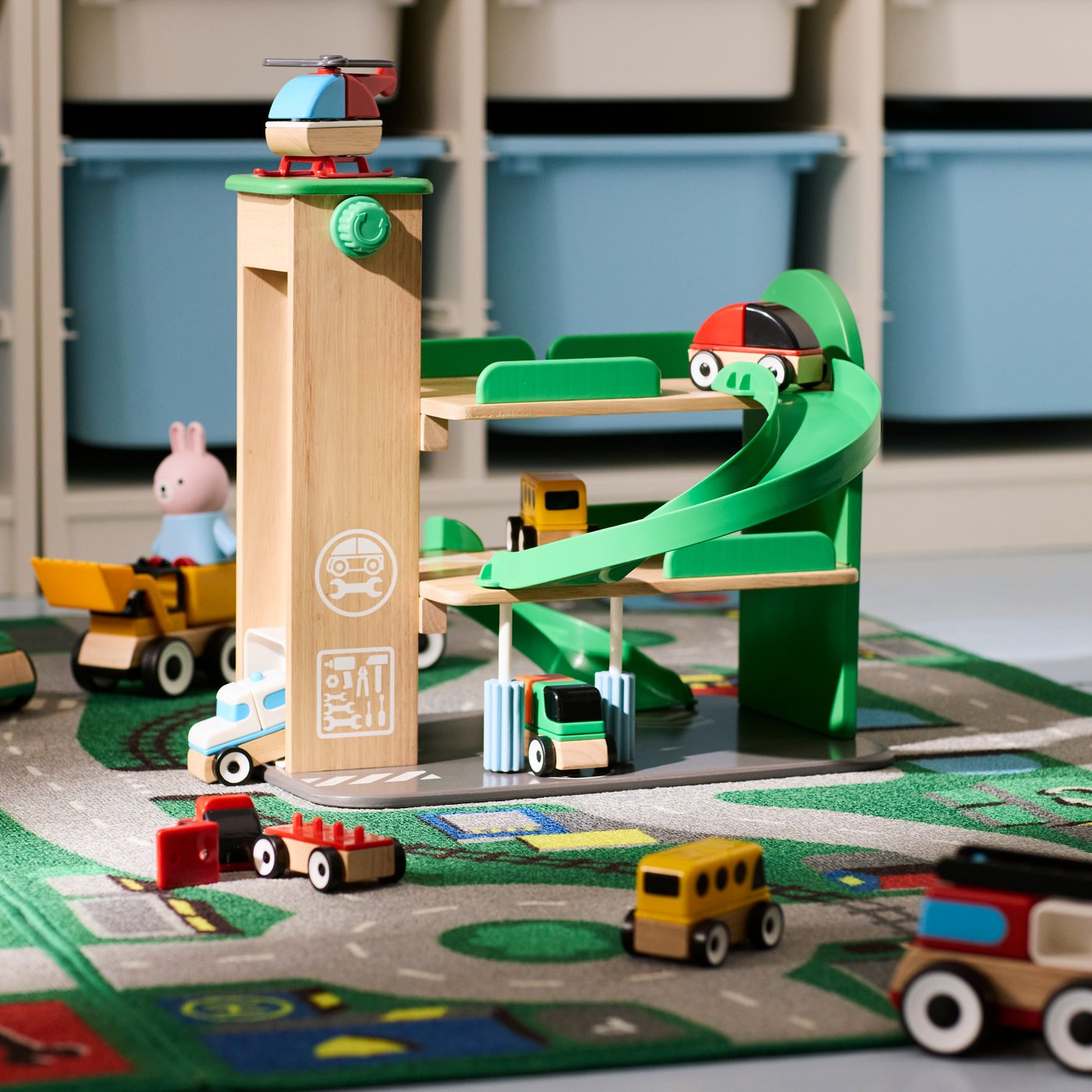 The complete LILLABO garage with helicopter and a lot of toy vehicles rolling around the garage, ramp and rug.