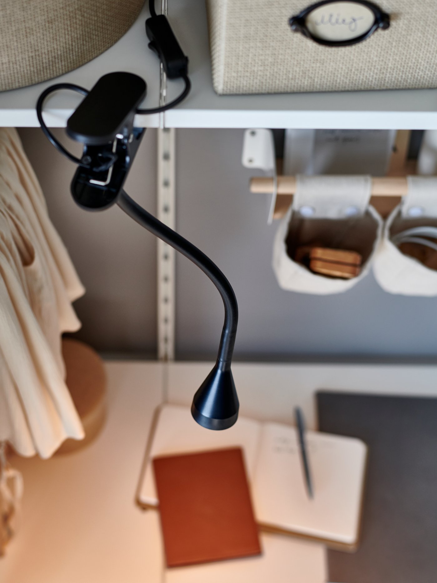A black NÄVLINGE LED clamp spotlight in a homeworking area