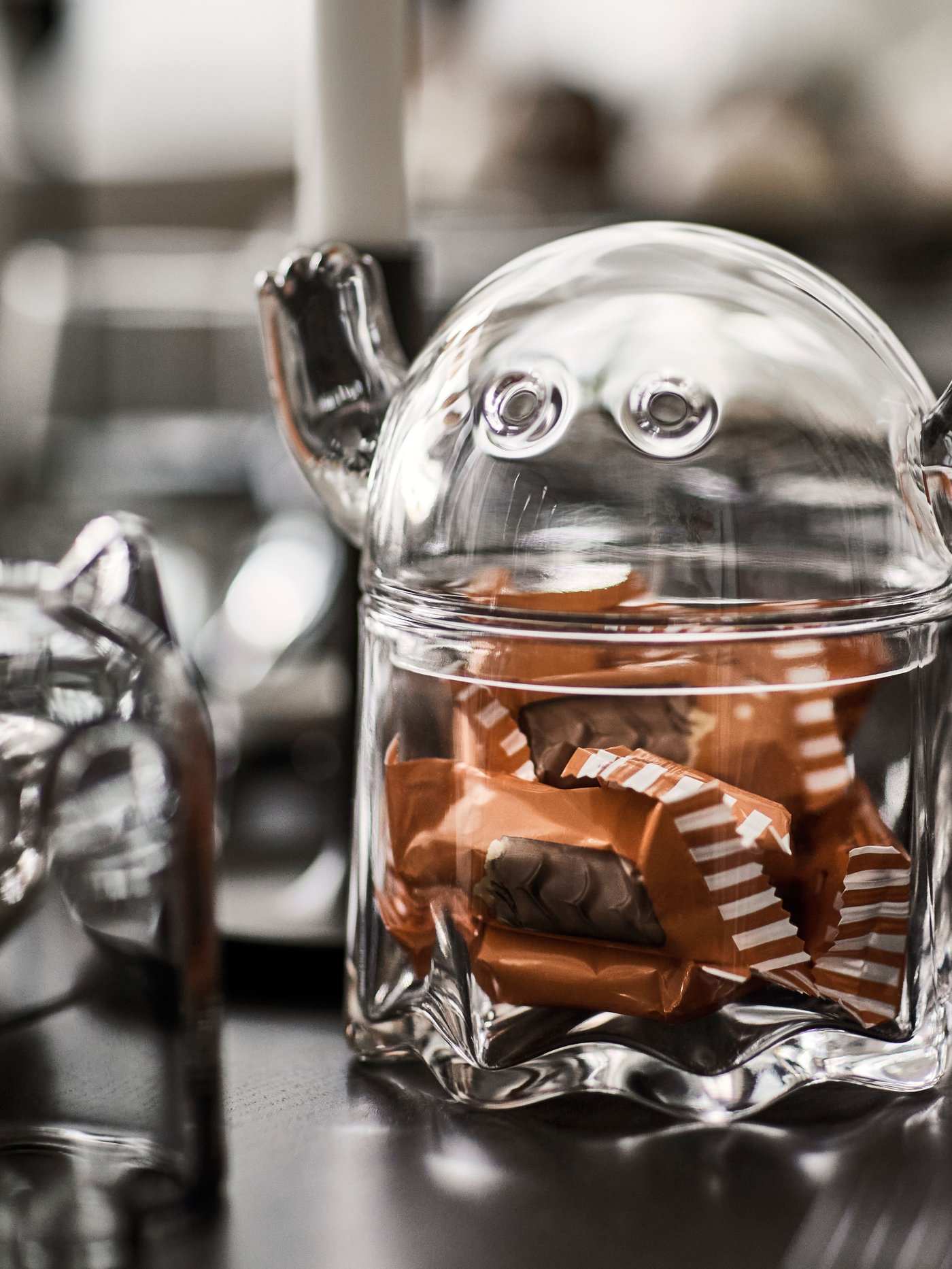 Adskillige chokolader kommer ned i KUSTFYR skålen med låg. Det lykkes en sidste chokolade at flygte ud ad billedet.